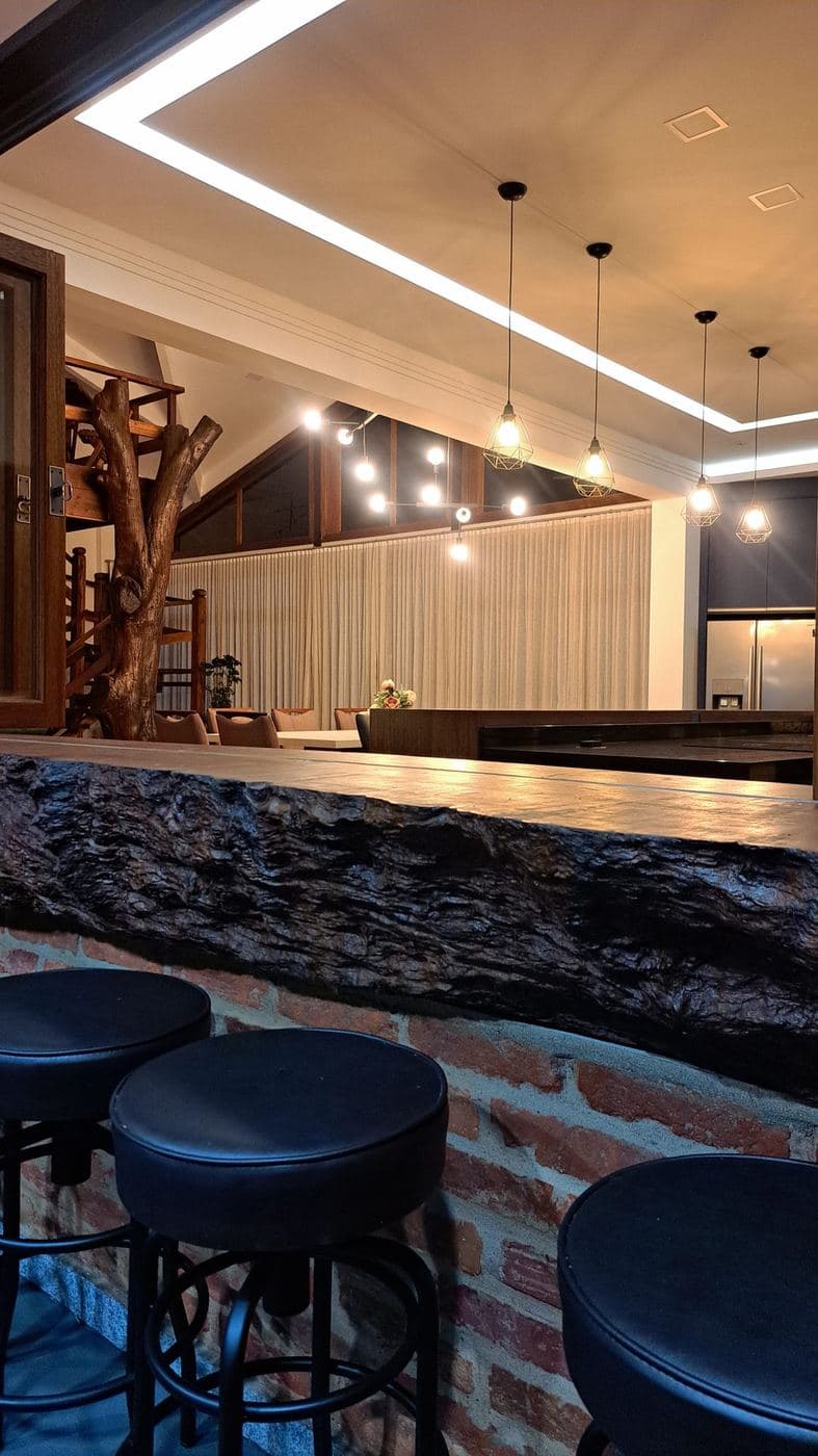 Área gourmet: Pendentes com lâmpadas aparentes sobre o balcão e linha de LED no forro.