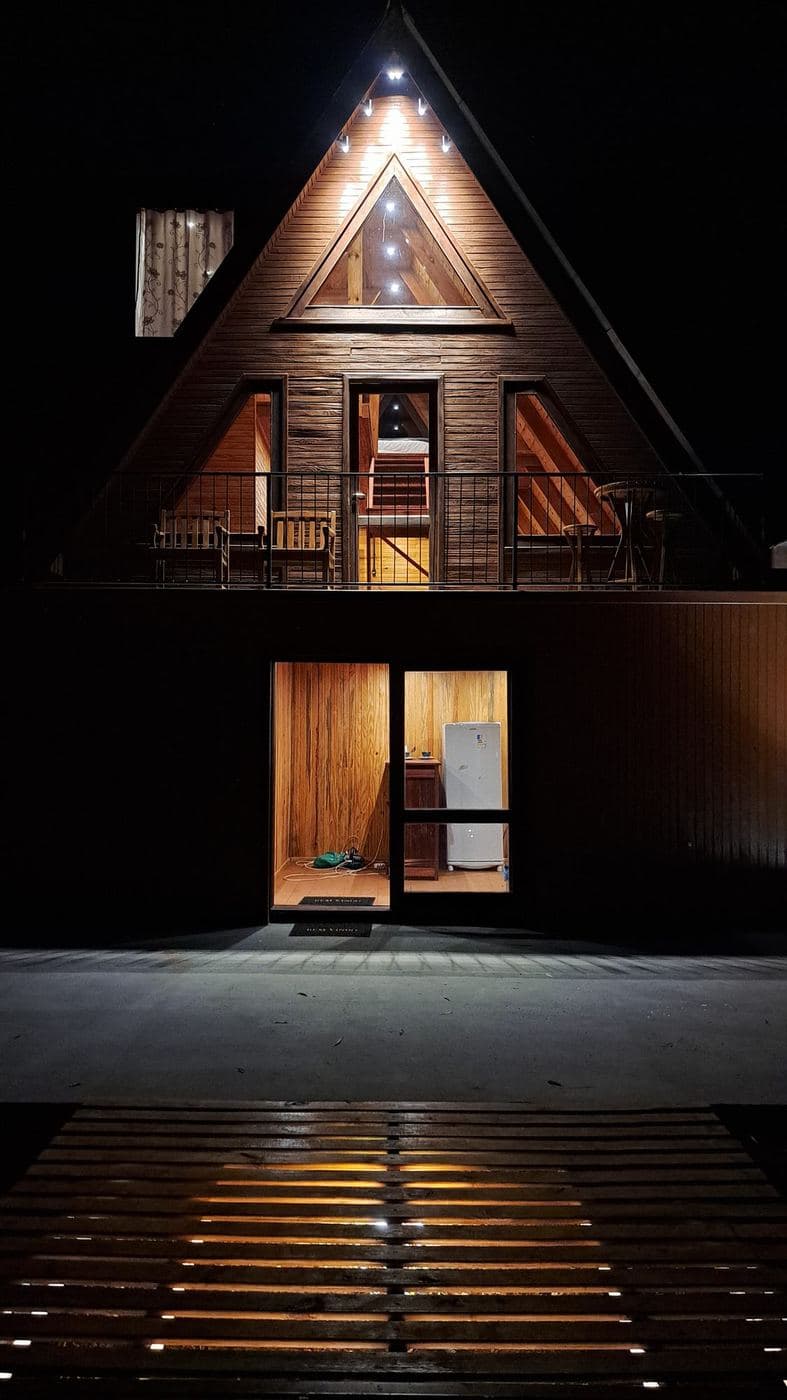 Chalé: Spots no beiral, luz na entrada e balizadores no deck para destacar a fachada triangular.