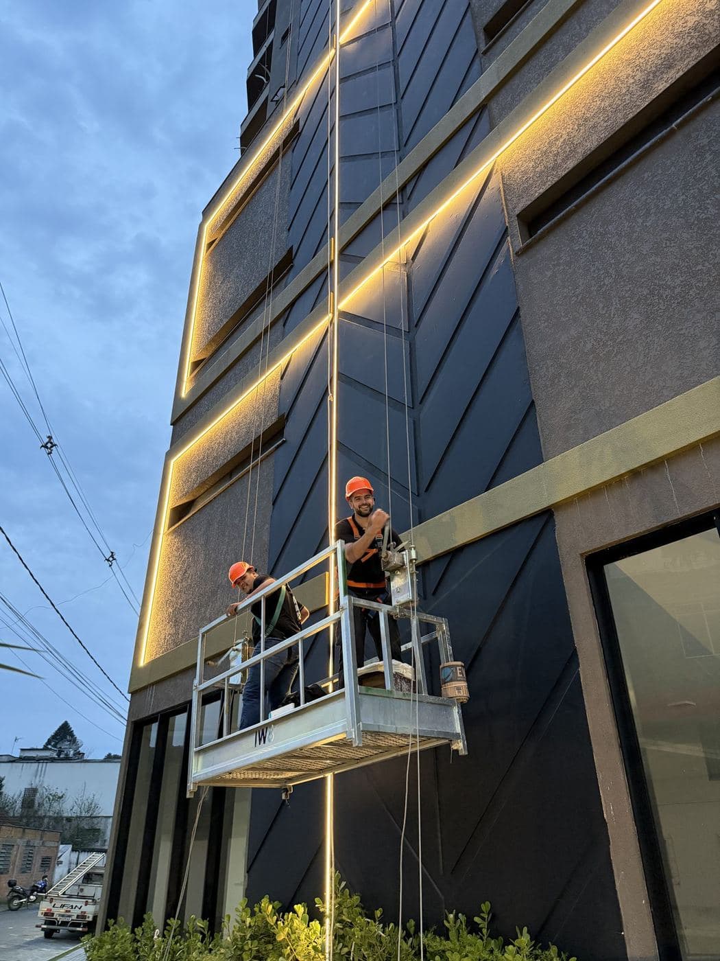 Fachada de edifício: Instalação de perfis de LED na fachada de um prédio, feita com balancim em altura.