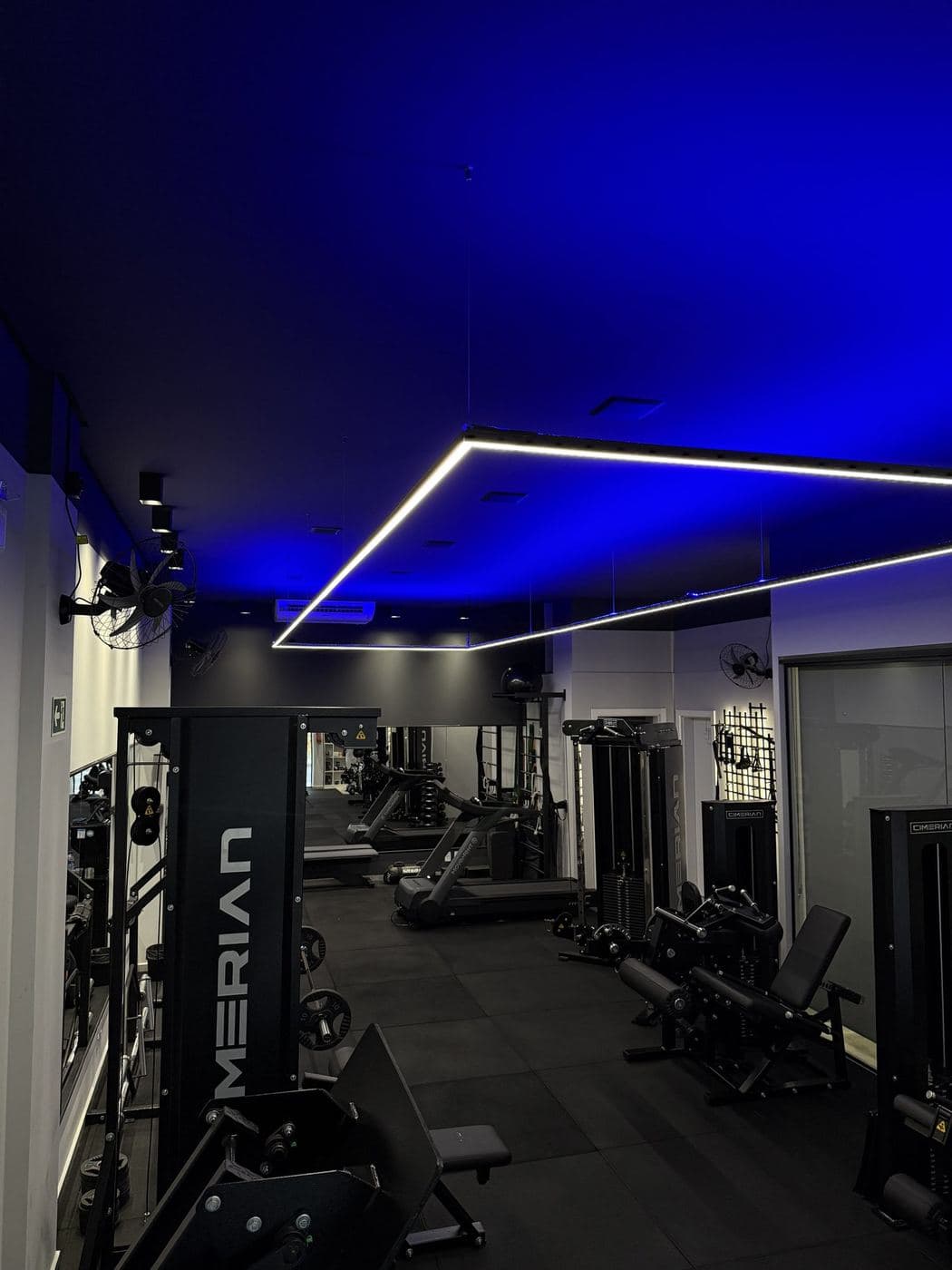 Academia, musculação: Sanca com LED azul e retângulo de perfil de LED branco no forro.