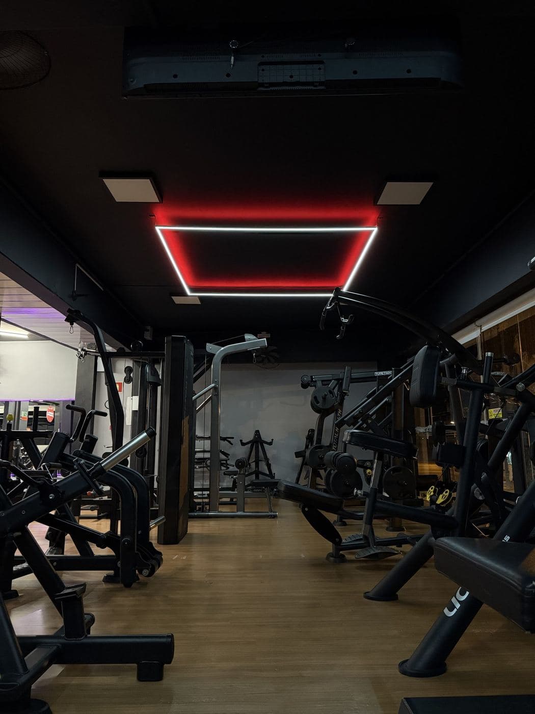 Academia, aparelhos: Quadro de LED vermelho no forro sobre a área de aparelhos.