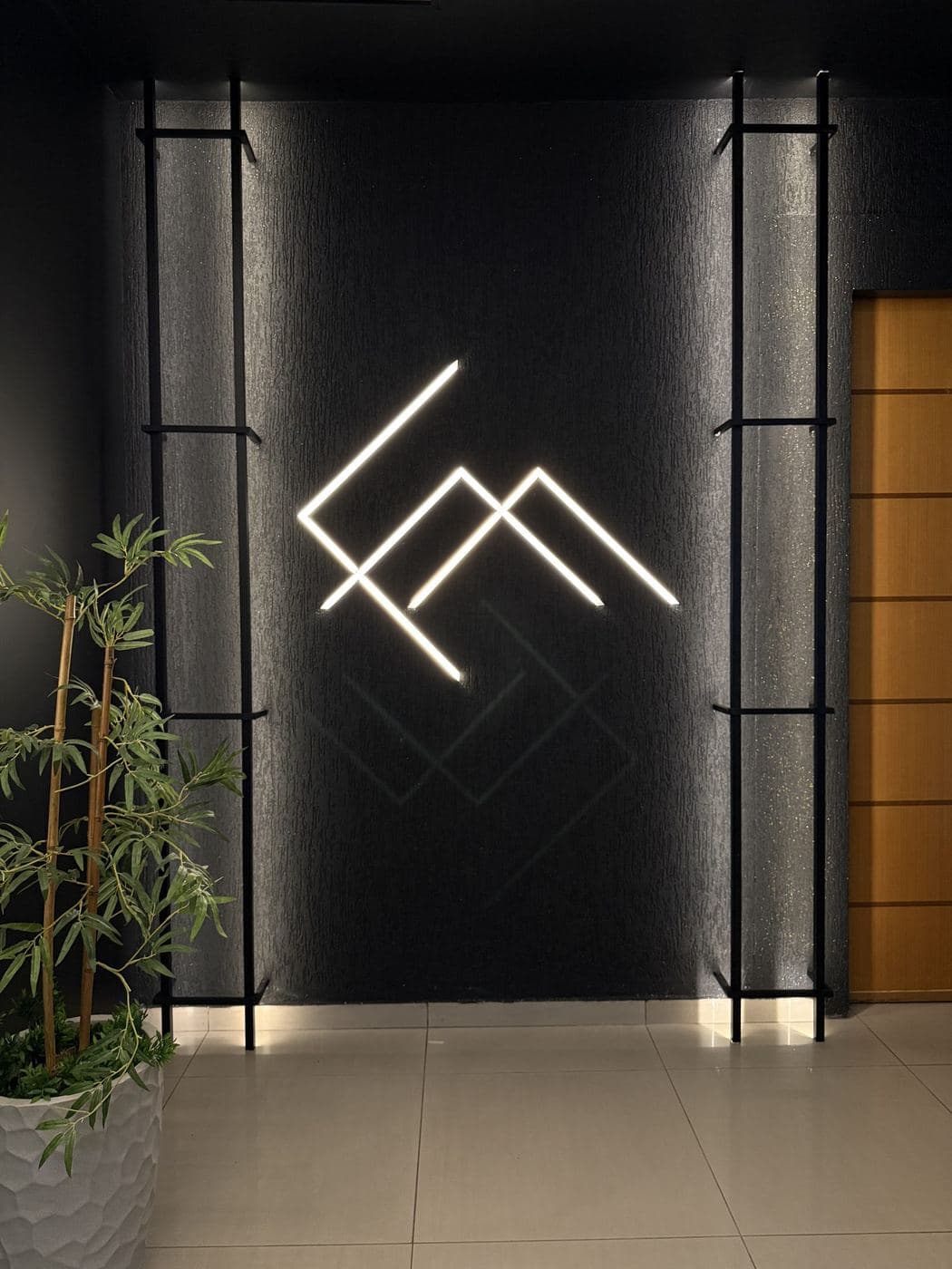 Recepção de academia: Logotipo desenhado com perfis de LED e luz de destaque nos pilares.