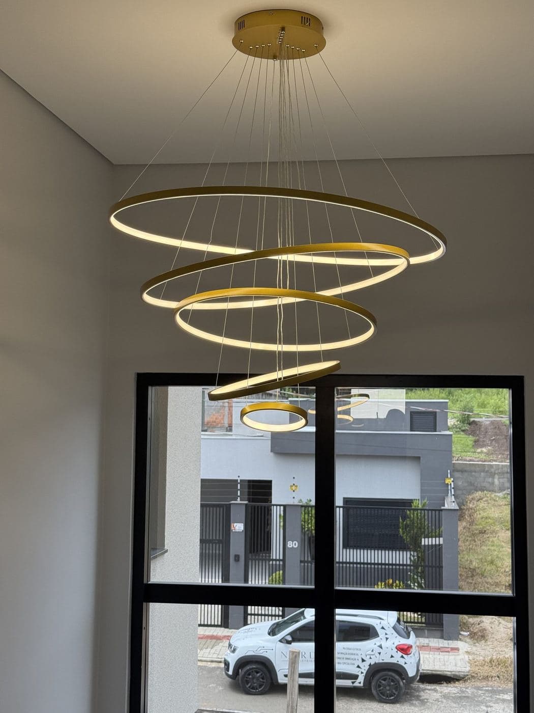 Pendente de anéis: Pendente de anéis dourados de LED no pé-direito duplo.