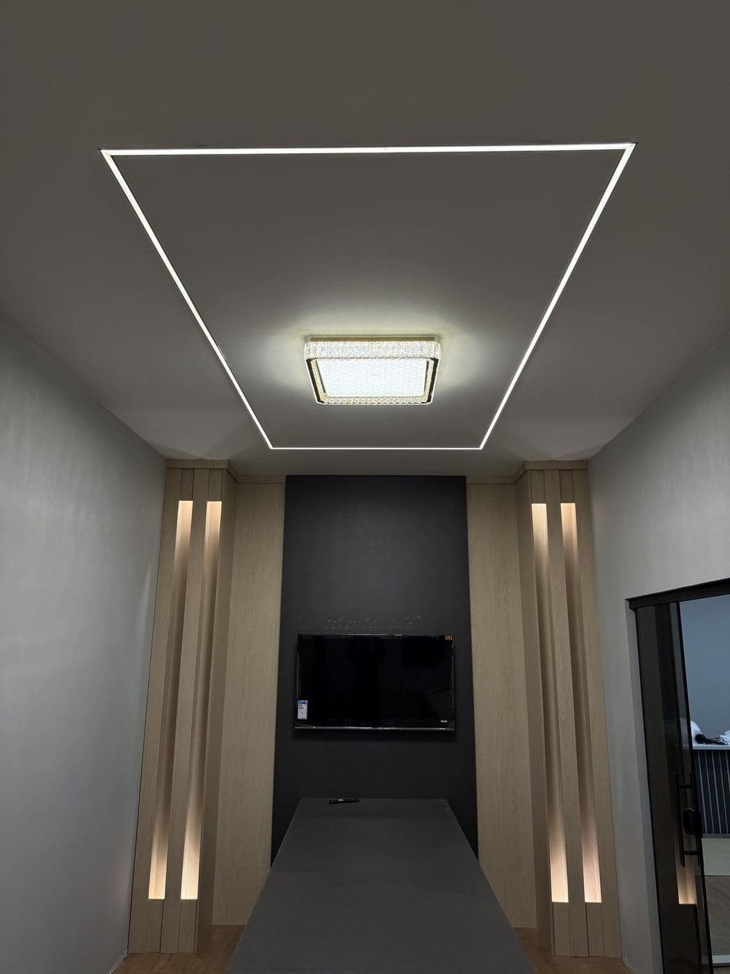 Sala de TV com nichos: Retângulo de perfil de LED no forro, plafon central e nichos verticais com LED ao lado da TV.