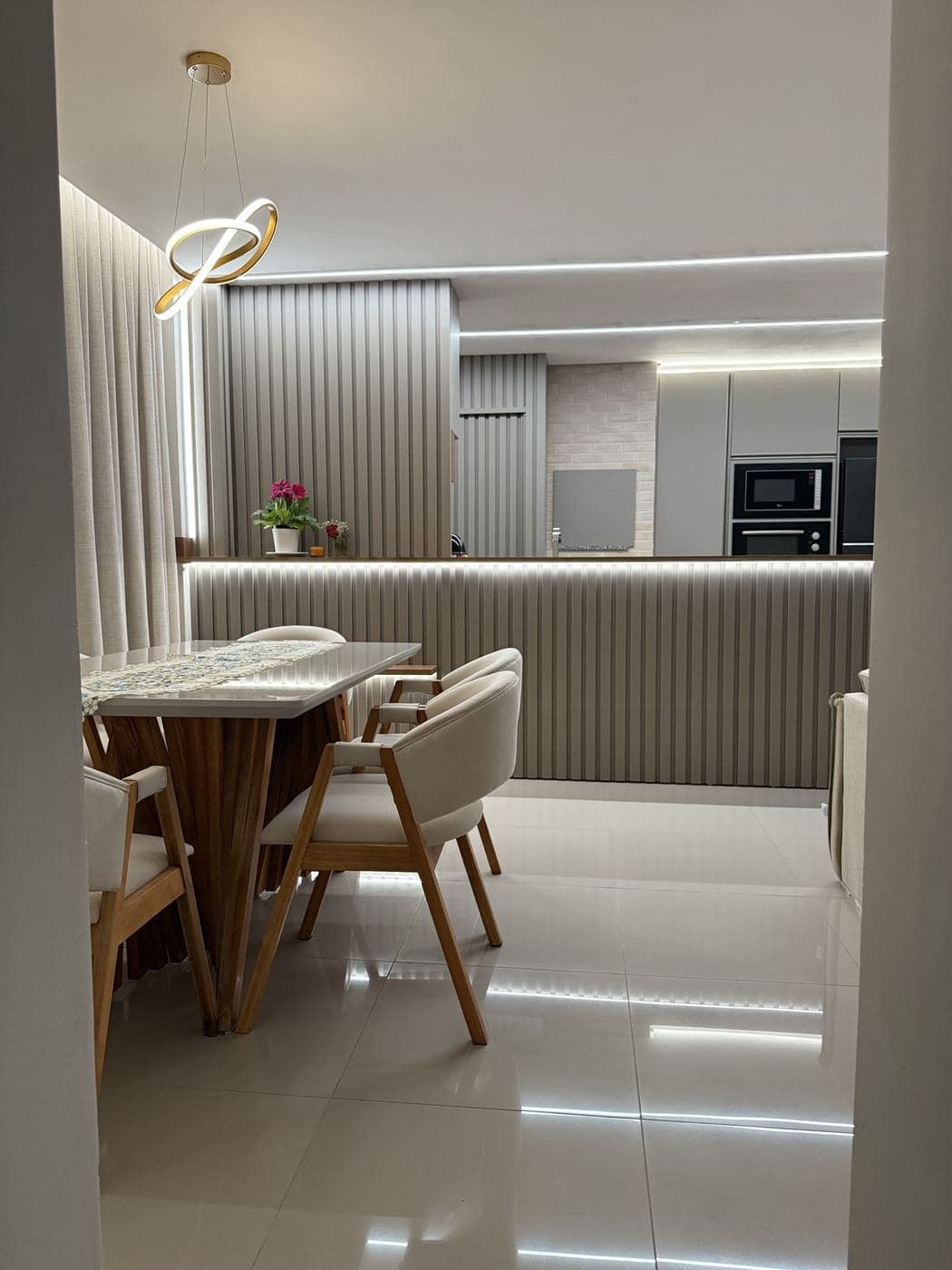 Sala de jantar e cozinha: Pendente de LED sobre a mesa, fita de LED no balcão e luz rente ao piso.
