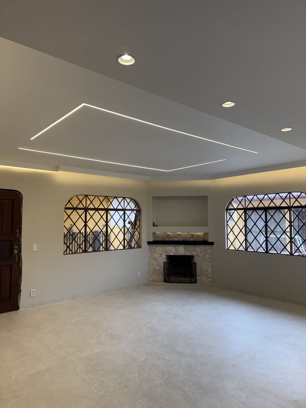 Sala com lareira: Retângulo de perfil de LED no forro e spots embutidos destacando a lareira.