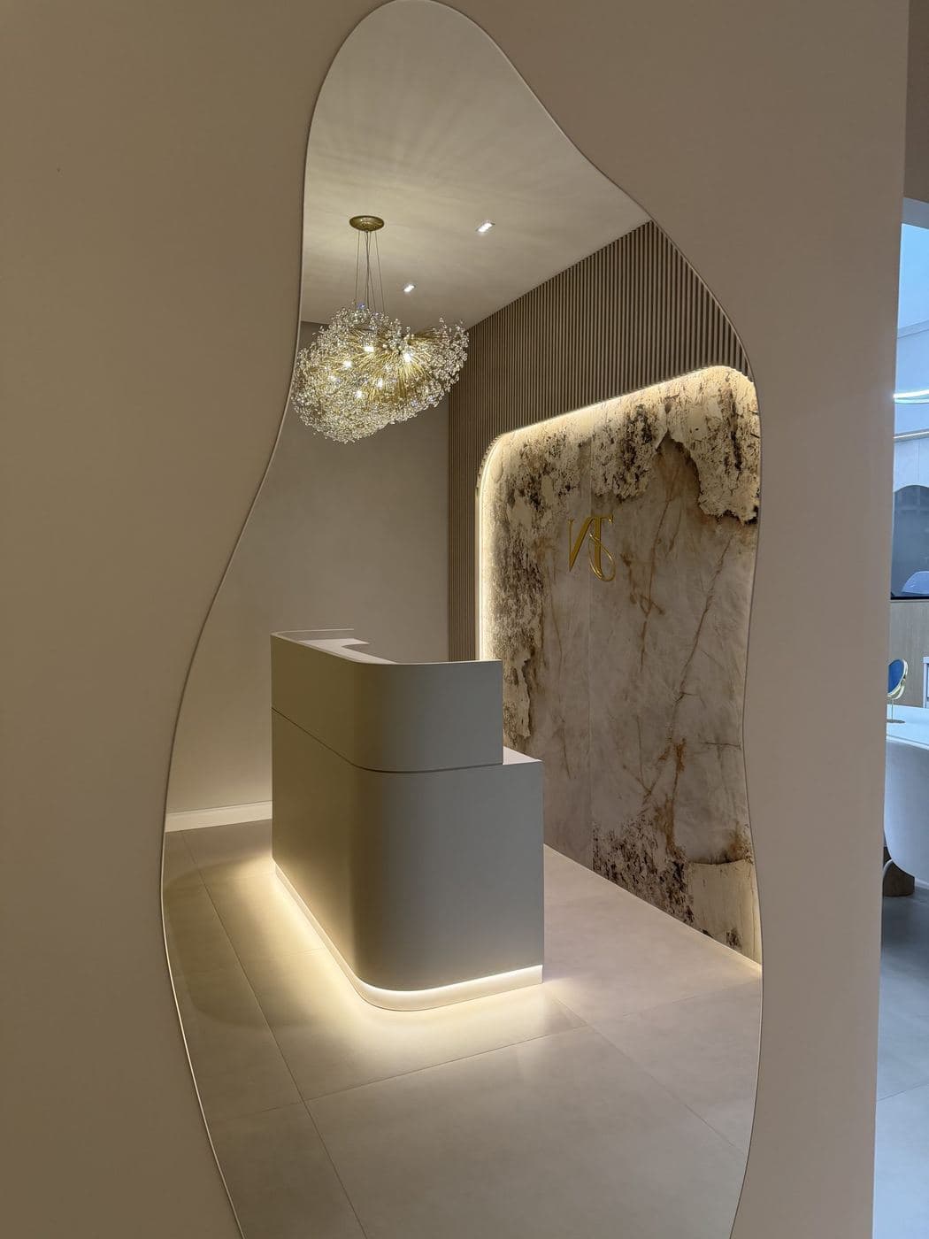 Balcão de recepção: Fita de LED na base do balcão e no painel de pedra, com pendente de cristal.